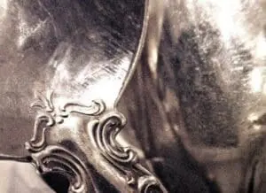 Ornate silver spoon with decorative handle being polished