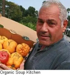 Man holding fresh organic squash at soup kitchen produce display