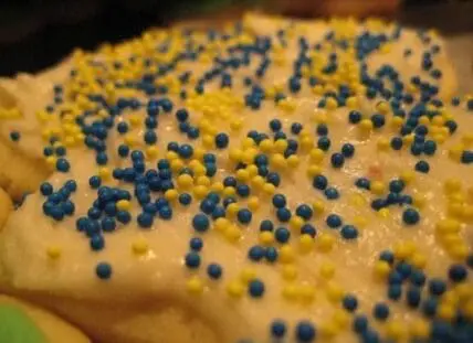 Close-up of yellow frosted dessert topped with blue and yellow sprinkles