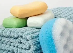 Bars of colorful soap and a blue exfoliating sponge on a textured washcloth