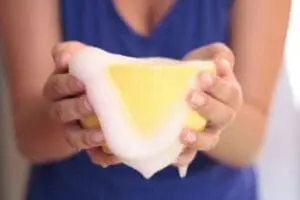Hands holding a yellow and white bar of homemade soap