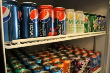 Shelves of plastic beverage cans and bottles in a refrigerator