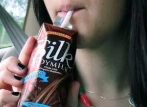Woman holding a carton of chocolate soy milk beverage