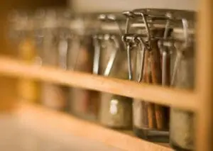 Glass jars of spices displayed on wooden shelf