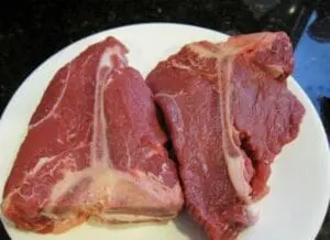 Raw red meat steaks on a white plate