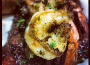 Grilled fish fillet with lemon and herbs on dark plate