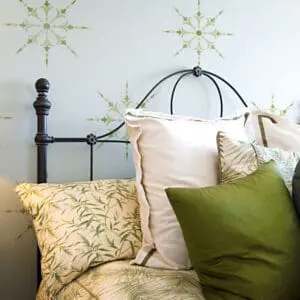 Bedroom wall decorated with stenciled snowflake patterns above an ornate black bed with patterned
