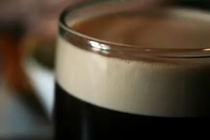 Glass of dark stout beer with thick cream-colored head