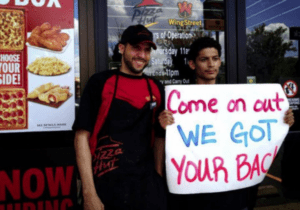Fast food workers holding a sign reading "Come on cut WE GOT YOUR BACK" during a strike protest