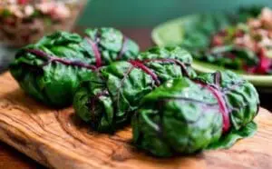 Fresh Swiss chard bundles with green leaves and purple stems on a wooden cutting board