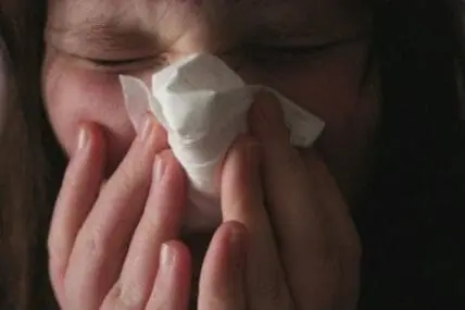 Person holding tissue to their nose while sneezing or blowing nose