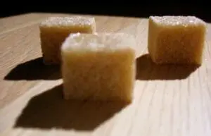 Sugar cubes dusted with granulated sugar on a wooden surface