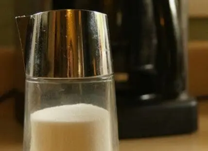 A glass of milk with a metal measuring cup on top