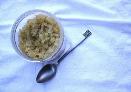 Homemade coconut vanilla sugar body scrub in a clear container with a spoon
