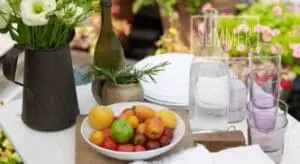 Outdoor summer table setting with fresh fruit, flowers, and beverages for entertaining guests