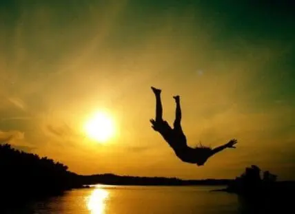 Silhouette of a person diving into a river at sunset