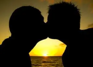 Silhouetted couple kissing at sunset over the ocean