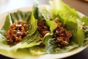 Lettuce wraps filled with seasoned ground meat on a white plate