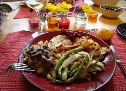 Homemade holiday dinner plate with roasted vegetables and meat sides on festive table setting