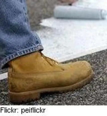 Close-up of a tan Timberland boot worn with jeans on asphalt