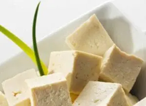 Cubed tofu with green onion garnish in white bowl