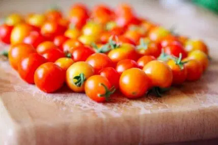 Fresh cherry tomatoes arranged on a wooden cutting board