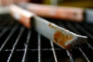 Brush with homemade condiment on grill grates