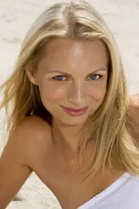 Woman with blonde hair smiling at camera in white draped clothing