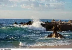 Waves crashing against rocky outcrops along a sandy beach