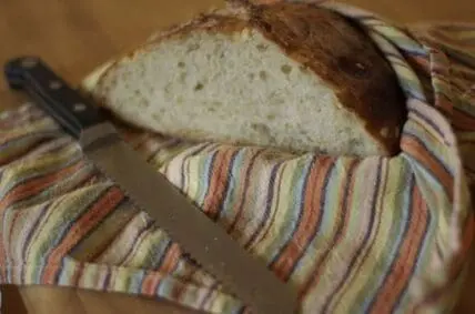 Sliced bread on a striped kitchen towel with a serrated bread knife