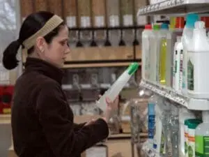 Woman reading product label while shopping for household cleaning supplies