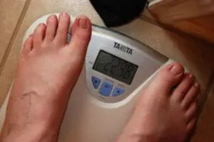 Person's swollen feet on a bathroom scale displaying weight measurement