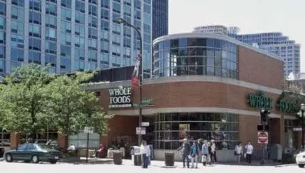 Whole Foods Market storefront on an urban street with pedestrians and tall buildings visible