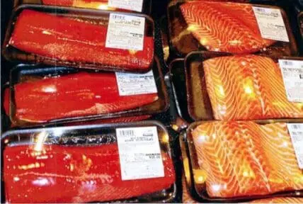 Packaged salmon fillets displayed in market trays with price labels