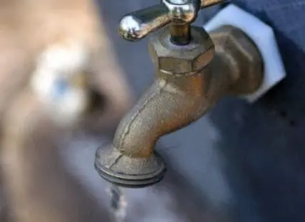 Rusty outdoor water tap with water dripping from the spout