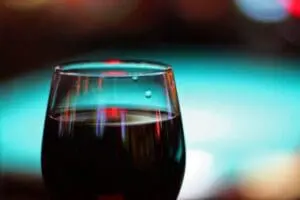 Glass of dark red wine with colorful bokeh lights in the background