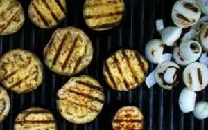 Grilled eggplant slices and onions on a barbecue grill