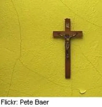 Wooden crucifix mounted on a bright yellow wall