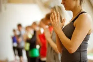 Fitness instructor leading a group exercise class with participants in the background