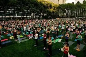 Large outdoor yoga class in an urban park with hundreds of participants on mats