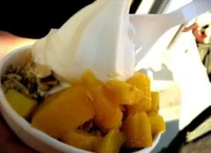 Vanilla yogurt with granola and sliced peaches in a white bowl