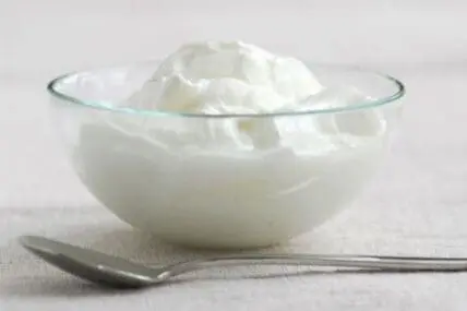 Creamy white yogurt in a glass bowl with a spoon