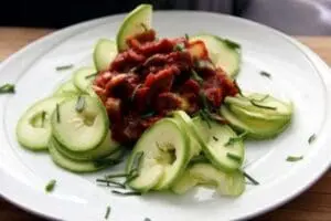 Sliced zucchini arranged on a plate with beets and chives