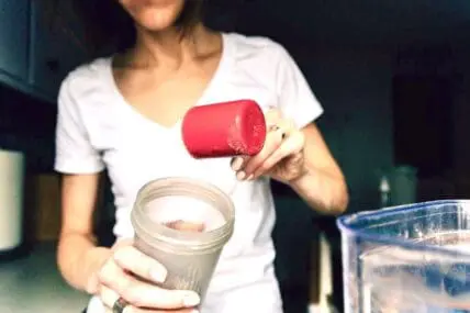 woman pouring powder into drink bottle