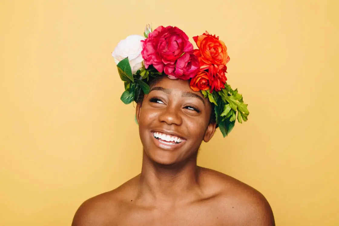 woman with beautiful skin with flowers on head smiling. collagen powder, peptides and supplements can help support beautiful skin