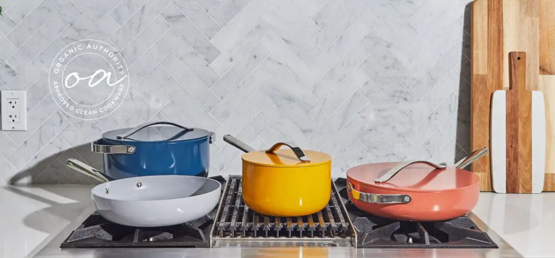 Image of Caraway Home cookware in multiple colors on a modern stove top with grey and white marble herringbone tile backsplash and smooth white countertop surface.