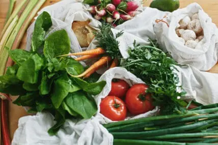 Image of fresh produce: tomatoes, carrots, spinach, green onions, and mushrooms some are part of the Daily Dozen 2024 or the Clean 15. These lists help you choose the right produce in your grocery store to keep toxins out of your system.