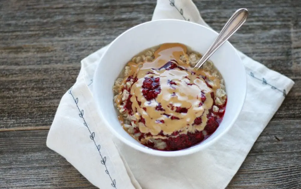 how to cook oatmeal breakfast garnished with toppings of jam and nut butter