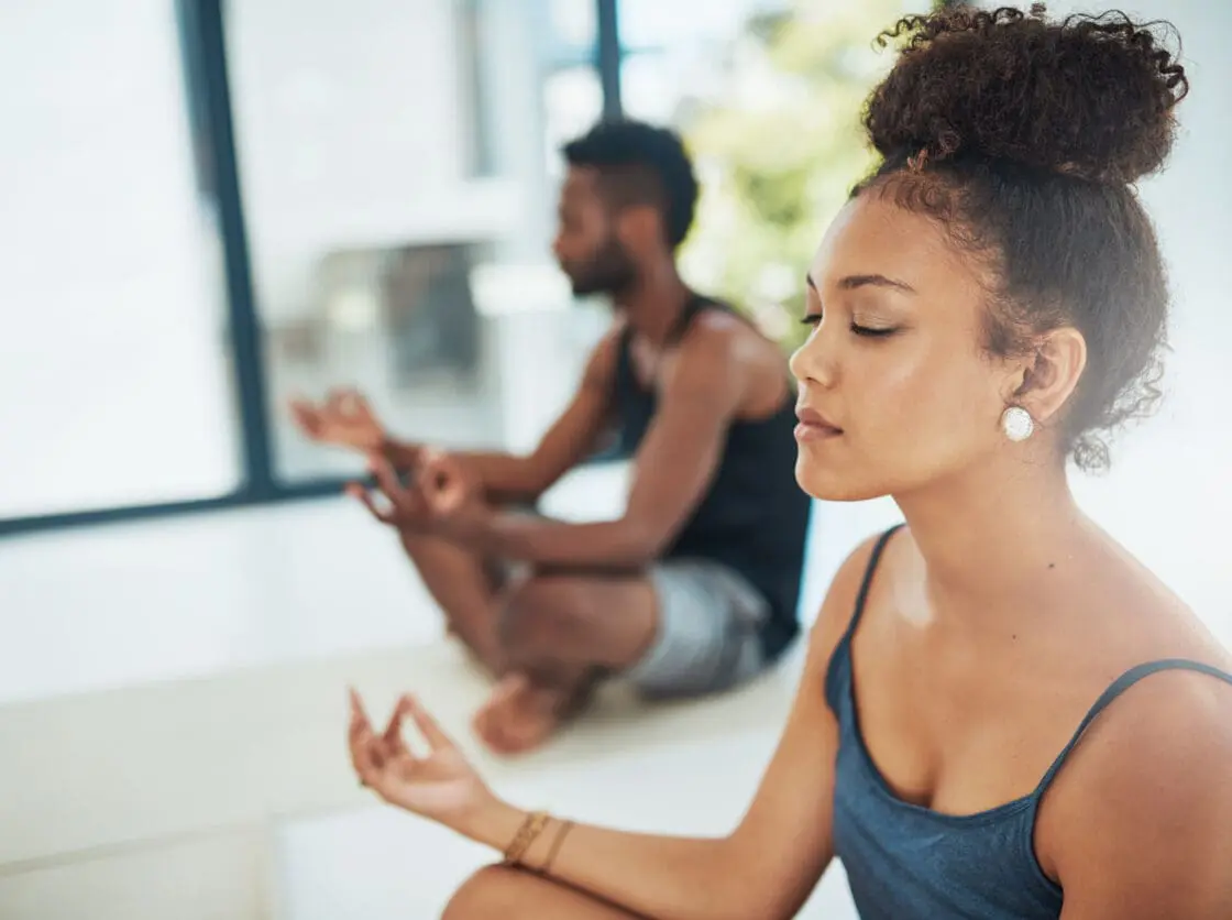 Shot of two people doing yoga together in a studio