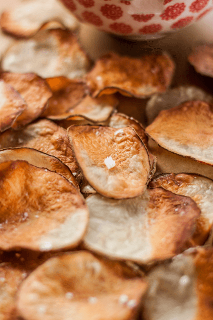 Image of a closeup of homemade baked potato chips with a small bowl of dip, healthier than their store-bought counterparts.